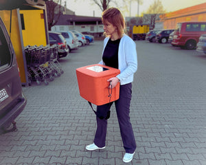 Frau trägt rückenschonend den AEROSTUFFY M und hebt ihn ins Auto