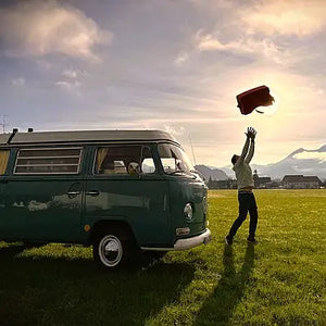 Anwendung VanLife mit AEROSTUFFY Box L rot hochgeworfen in die Luft neben einem VW T2 Westfalia