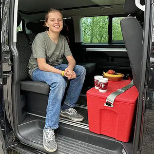 Junge sitzt im Van und nutzt die Kiste für eine Pause